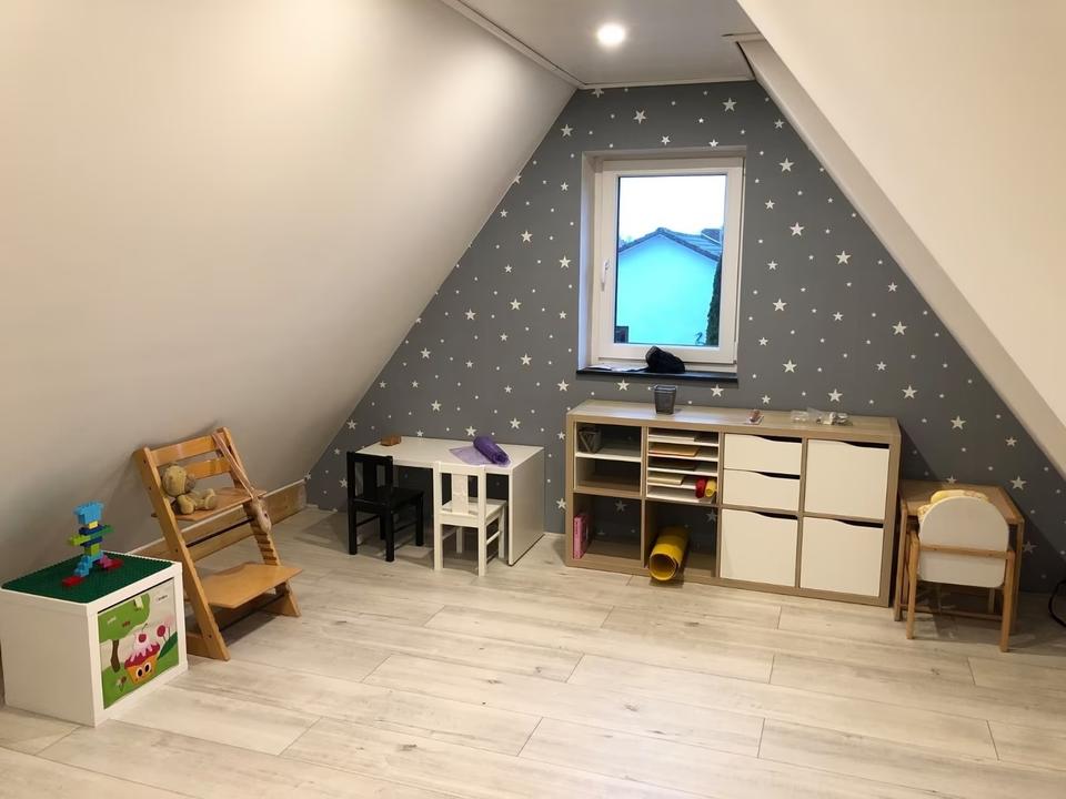 Kleiner Tisch mit Kinderstühlen und Sternentapete im Betreuungsraum